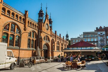Fototapeta premium Old town market - people buying goods next to the brick building. Gdansk, Poland