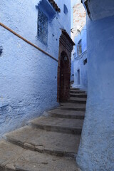 Narrow alleys with entrance doors to  houses in the blue city of Chefchaouen, Morocco