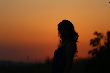 silhouette of a girl with curly hair at sunset.