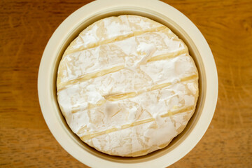 Close up of helpful mould on the rind of traditional French Brie cheese sitting on the wooden table