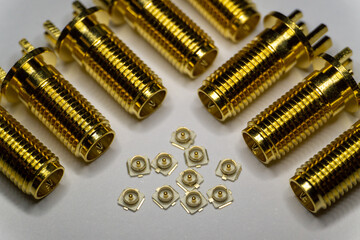 Close-up of symmetric aligned gold plated uFL micro precision radio connector in partial focus white and SMA background