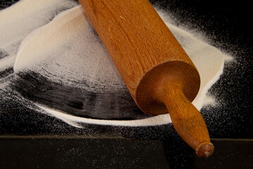 Rolling pin with flour on the black background