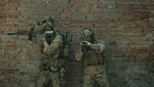Airsoft men back to back look around the corner with gun. Training to fight in urban territory. 