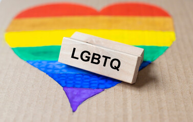 acronym LGBTQ on wooden block on lgbtq flag in heart form.