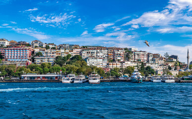 Fototapeta premium Cityscape of Üsküdar with colorful buildings, little mosque and pier with moored boats during the daytime. Üsküdar, Istanbul, Turkey