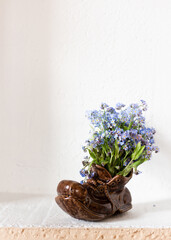 Ceramic slipper with a bouquet of forget-me-nots on a white background