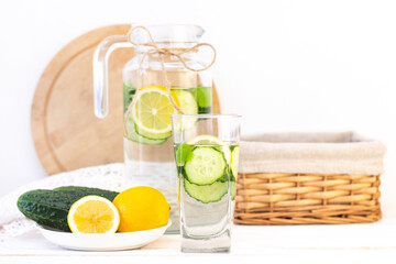 Health care, fitness, healthy eating concept. Fresh cool lemon cucumber drink with water, cocktail, detox drink, lemonade in a glass jug and a glass. cucumbers and lemon on a plate