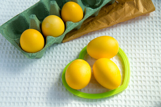 Preparing for Easter. Painted yellow eggs lie on a white waffle towel and in a craft green egg box.