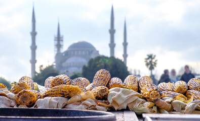 Baked corn on a street vendor cart in the historical center of Istanbul, Turkey with a blue mosque...