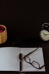 Still life con reloj antiguo sobre escritorio con libros, reloj despertador, gafas y fondo negro o...