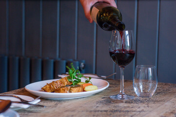 red wine being poured beside a meal