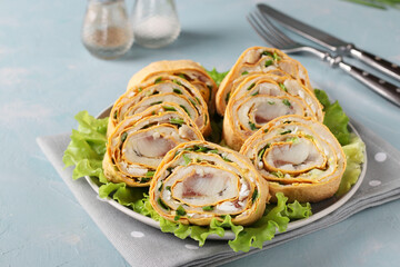 Pita roll with herring, potatoes and onions on light blue background, horizontal orientation, closeup