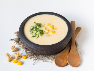Vegan corn soup puree in a wooden bowl in rustic style on a light background 