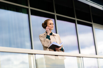 Young beautiful businesswoman with sunglasses, phone, laptop, cup of coffee in the city streets.