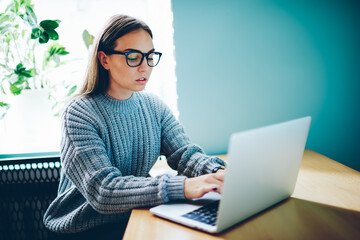Clever female student writing information from online research doing homework 