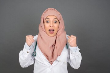 Caucasian young doctor woman rejoicing her success and victory clenching her fists with joy. Lucky woman being happy to achieve her aim and goals.