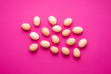 Chicken eggs flat lay on a pink colored background