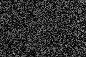 A hand-drawn surface with doodles, swirls, and zigzags on a black background. Abstract monochrome...
