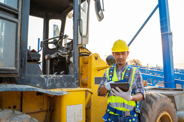 Construction worker with backhoe loader on the background at construction site.