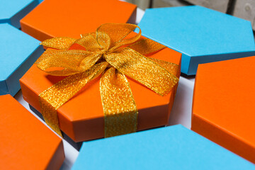 A close up beautiful blue and orange hexagon gift boxes on the white background. One of them with bright ribbon and bow. Place for text. Empty boxes. Top view. Flat lay
