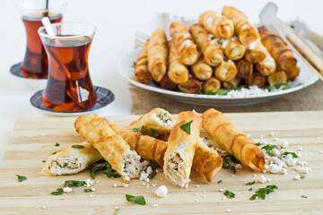 Traditional Turkish  "Sigara Borek" Rolls are savory, cheesy and crunchy made with just cheese and parsley.Cut on wooden board and served with Turkish Tea.
