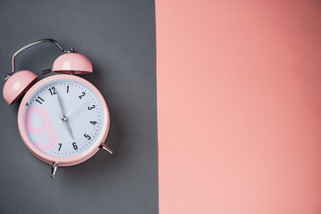 Detail close up of the old pink vintage alarm clock on colour background with free copy space.