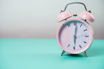 Detail close up of the old pink vintage alarm clock on colour background with free copy space.