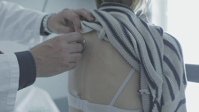 Doctor auscultando a mujer con estetoscopio