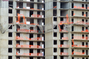 Abandoned high-rise construction site with torn orange bounding grids