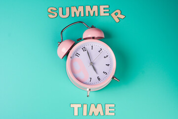 Summer time. Detail close up of the old pink vintage alarm clock on colour background.
