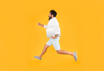 Running into busy life. Busy man in midair yellow background. Energetic hipster run with laptop pc. Busy schedule. Business communication. Modern life. New technology. Being busy and active