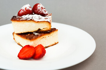 Cottage cheese casserole with strawberries  on grey background, closeup view