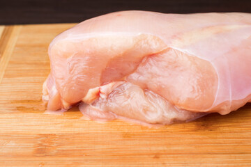 Raw chicken breast on a wooden cutting board