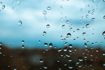 Gotas de lluvia sobre el cristal de una ventana en un día nublado. - obrazy, fototapety, plakaty