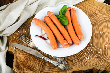 sausages with herbs on a white plate wooden background