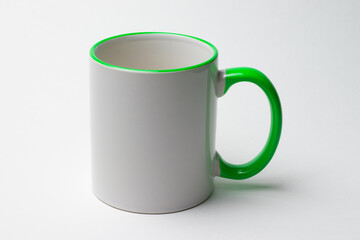 Ceramic white mug with a green handle on a white background.