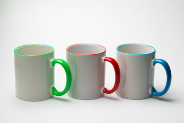 Three ceramic mugs with multi-colored handles on a white background