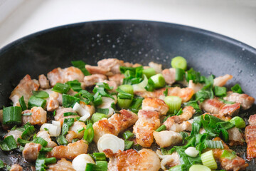 Fatty pork with green onions fried in a pan. Copy space.