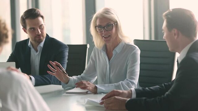 Business meeting lead by middle aged woman in modern boardroom, business parties company representatives meet for plan future collaboration, discuss terms conditions sign contract solve issues concept