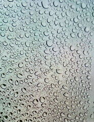 After the rains, raindrops on the glass formed a natural textural pattern. Rainwater gathered in drops on the clear glass of the window. Textured background.