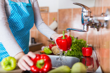 Close up of woman hands washing vegetables in modern kitchen.