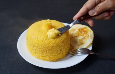 Mão feminina colocando manteiga no cuscuz. Comida típica do Nordeste do brasil. Cuscuz...