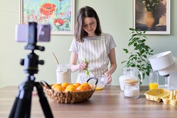 Girl teenager food blogger cooking orange pancakes at home in kitchen