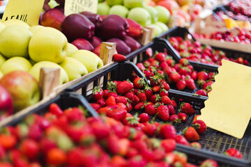 Boxes of fresh strawberries and apples on fruit market