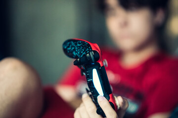 Chico jugando a la video consola. Detalle del mando en la mano. Bokeh
