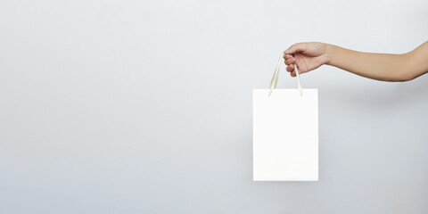 Fototapeta na wymiar Hands hold a paper bag for online food and grocery delivery on a white isolated background with a copy of the space. Concept of the courier business of buying and ordering