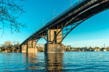 Arched bridge over the river. Concrete and metal construction