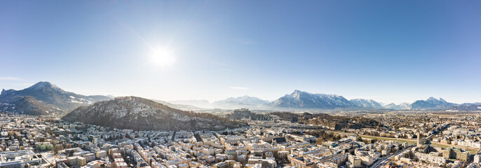 Panoramic aerial drone view of Salzburg snowy old town with view of Unesberg Kapuzinerberg mountain in winter morning