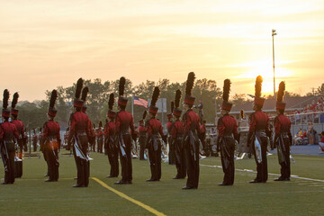 Marching band on a field at sunset. Marching in a line with trumpets and other instruments playing...