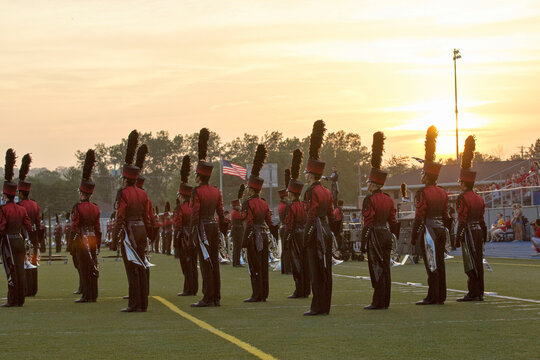 Marching band on a field at sunset. Marching in a line with trumpets and other instruments playing music. 